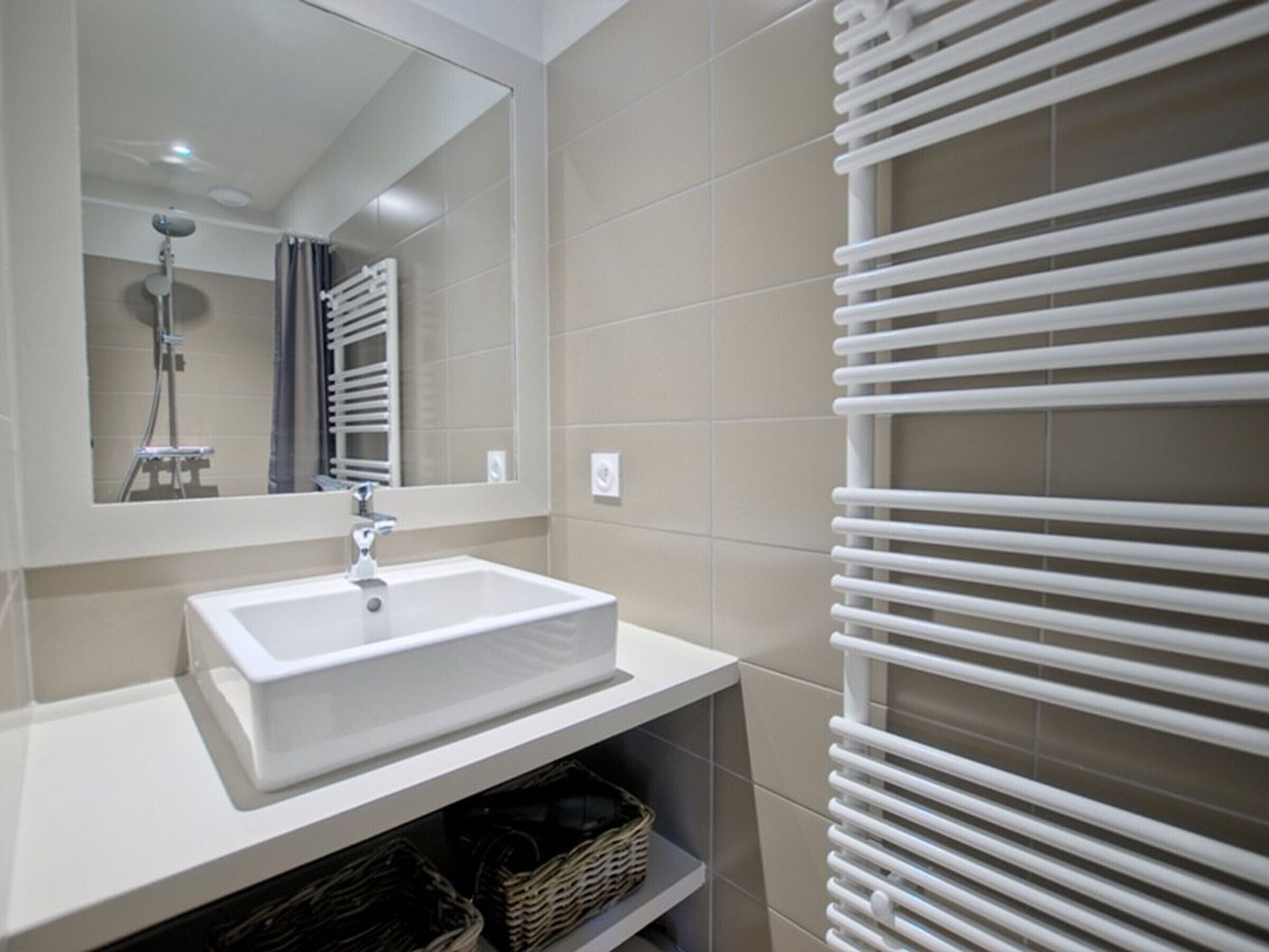 A modern bathroom with a white sink, a mirror, and a towel rack.