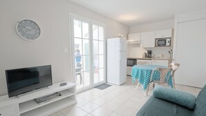 Een woonkamer met een flatscreen televisie, een bank en een eethoek met een tafel en stoelen.