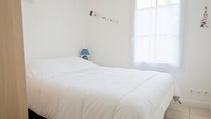 Een slaapkamer met een bed, een nachtkastje, een lamp en een raam.