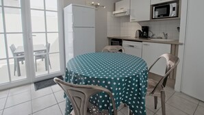 Een compacte keuken met een eethoek, met een koelkast, magnetron en een spoelbak.