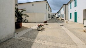 A narrow street lined with white buildings with green shutters, a bicycle, and potted plants. - Functional ground floor apartment with courtyard and secure garage (Saint-Martin-de-Ré)