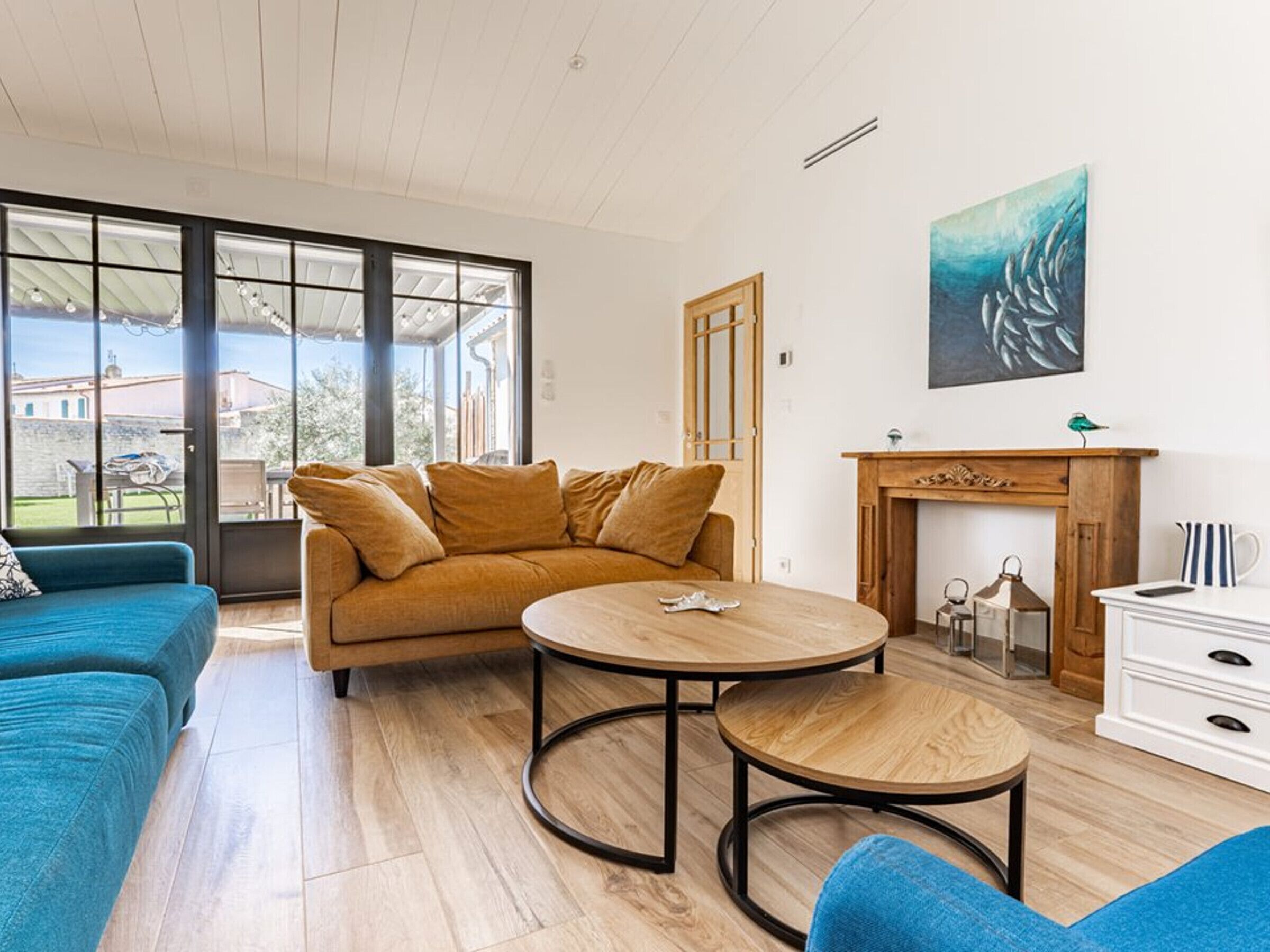 Een moderne woonkamer met een bank, een rond bijzettafeltje, een open haard en een groot raam.