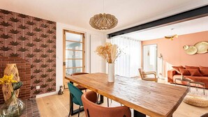 Un coin repas avec une table en bois, des chaises et un vase contenant des fleurs séchées.