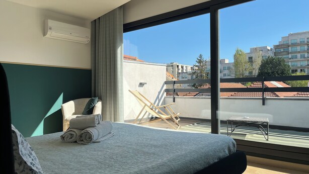 Ein Hotelzimmer mit Bett, Stuhl, Tisch und Blick auf die Stadt.