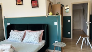 A bedroom with a bed, a bedside table, a lamp, and a mirror.