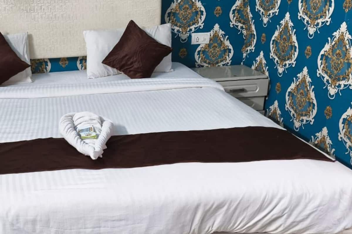 A neatly made bed with a brown and white striped bedspread, white pillows, and a folded towel on the bed.