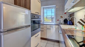 A modern kitchen with stainless steel appliances, a window with a view, and a wooden cabinet.