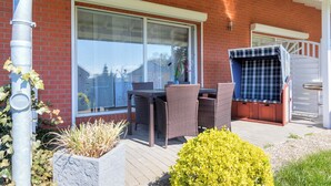 A patio with a table and chairs, a barbecue grill, and a large window.