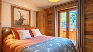Una habitación acogedora con una cama, un cuadro de un ciervo enmarco y vistas a una terraza de madera.