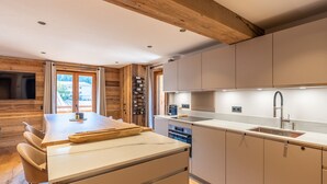 Una cocina moderna con vigas de madera, una isla central y una estantería empotrada para vinos.