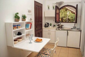 Una cocina compacta con cubierta blanca, un lavamanos y una ventana con cortinas.