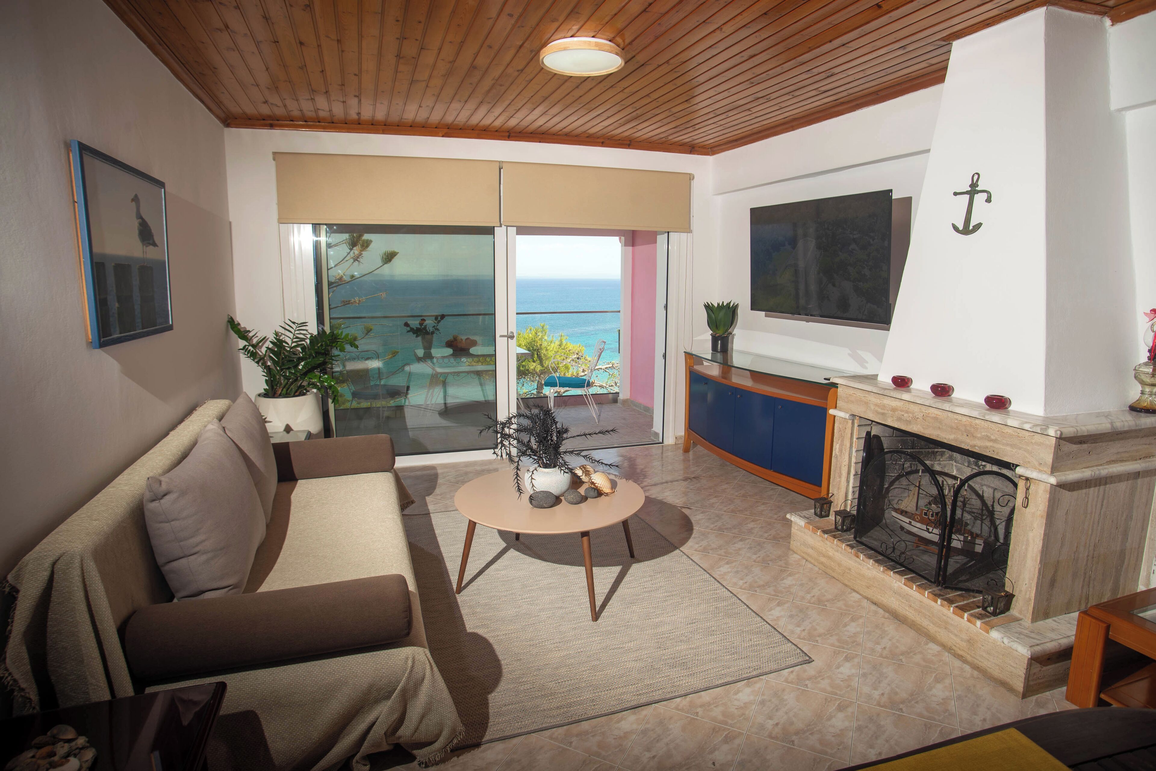 Una sala de estar con sofá, mesa de centro, chimenea y vista al mar a través de un ventanal corredero.