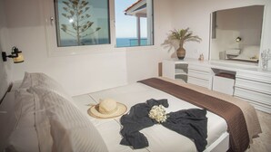 Ein Schlafzimmer mit einem Bett, einem großen Fenster mit Ausblick, einem Schminktisch und einem Spiegel.
