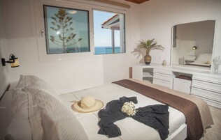 Un dormitorio con cama, un vestidor, un espejo y un amplio ventanal con vistas.