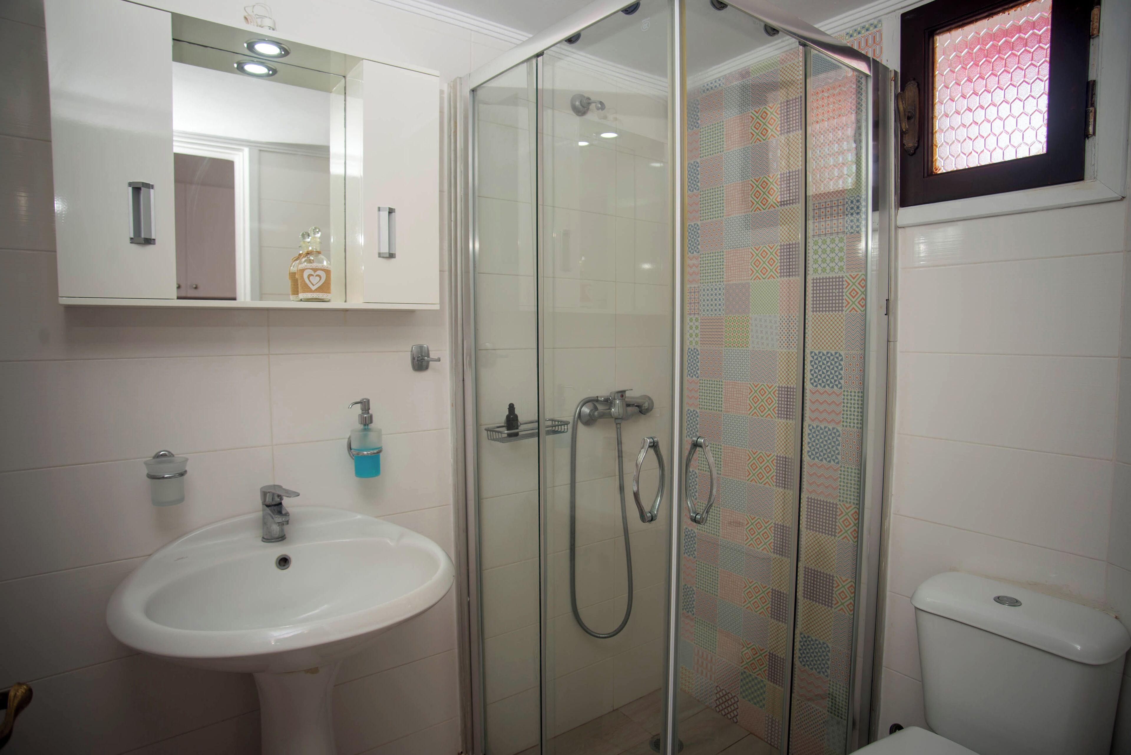 Une salle de bain avec une douche à parois de verre, un lavabo blanc et des toilettes.