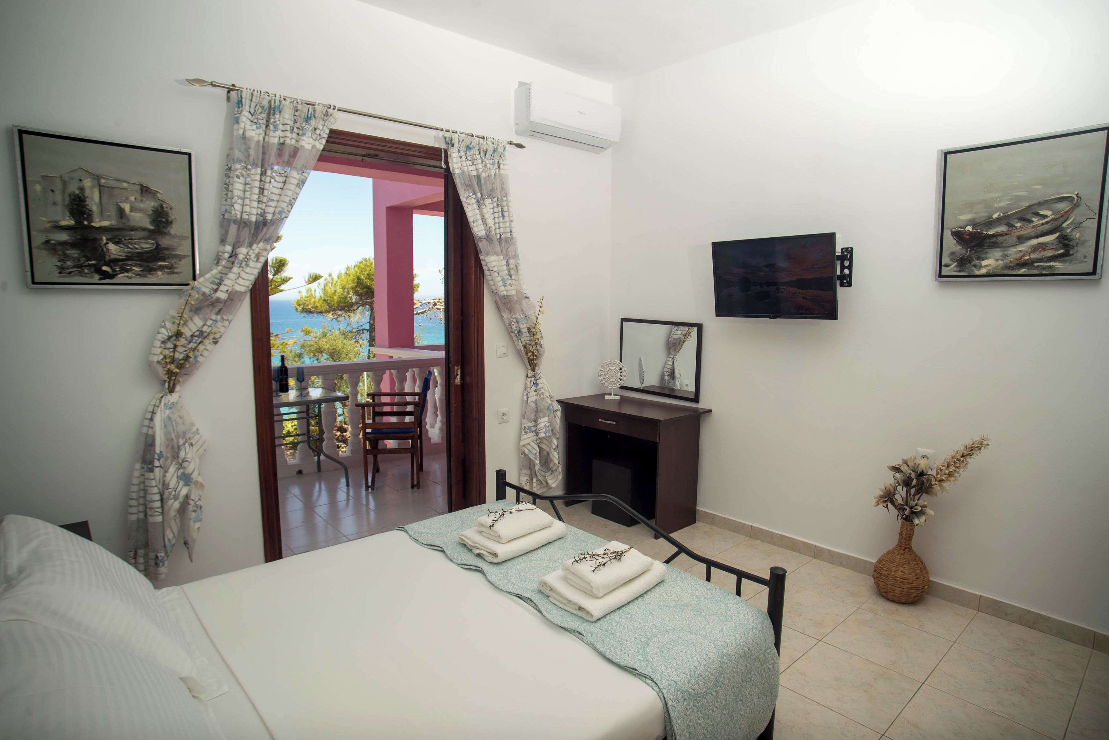 A bedroom with a bed, a desk, and a chair. There are two paintings on the wall.
