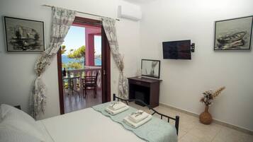 A bedroom with a bed, a desk, and a chair. There are two paintings on the wall.