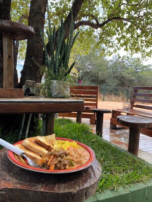 Une table à manger avec une assiette de nourriture, un banc et une plante en pot.
