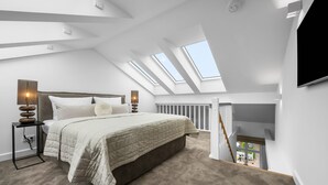 Un dormitorio moderno con tragaluz, una cama con colcha color beige, lámparas de noche y vistas al exterior.