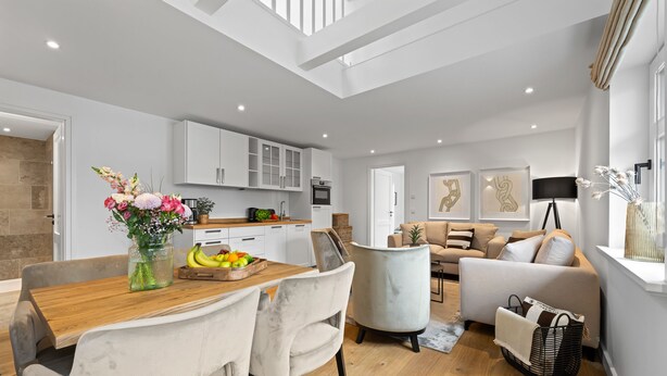 Una sala de estar moderna con comedor, cocina y escalera.