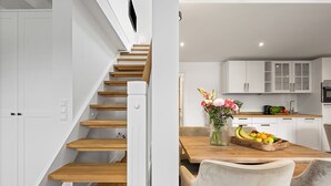 Una cocina moderna con armarios blancos, una mesa de comedor de madera y un frutero.