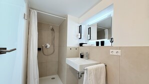 Un baño moderno con ducha, lavabo y espejo.