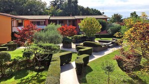 A well-maintained garden with a pathway leading to a building with a tiled roof. - Beautiful apartment for 3 guests with A/C, pool, TV, balcony and pets allowed (Lazise)