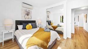 A modern hotel room with a large bed, a nightstand, a mirror, and a wooden floor. - Urban Escape 2BR Wifi Parking (Perth)