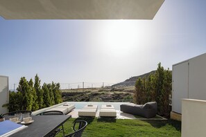 A patio area with a pool, outdoor seating, and a view of a hilly landscape.