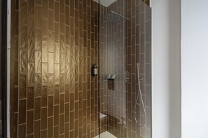 A modern bathroom with a shower area, tiled walls, and a glass door.