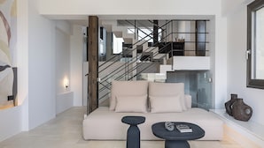 Una sala de estar moderna con un sofá, una mesa de centro y una escalera con barandilla.