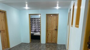 Una habitación amplia con suelo de madera, dos puertas y una cama con cortinas a la vista.