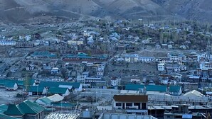 A town nestled against snow-capped mountains with buildings in the foreground. - Universal Comfort Guest House (Kargil)