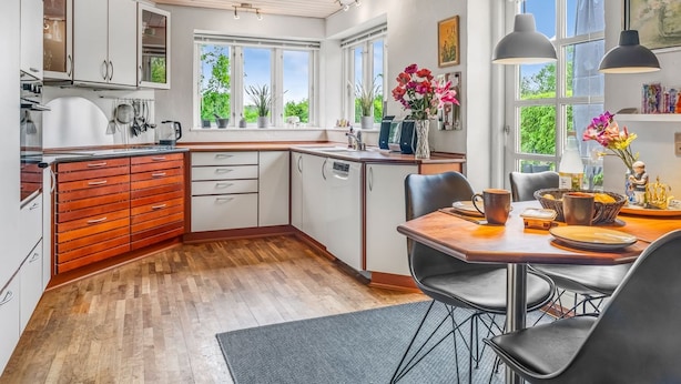 A modern kitchen with wooden cabinets, a dining area with a table and chairs, and large windows offering a view of greenery. - "Elza" - 2.5km from the sea by Interhome (Fjerritslev)