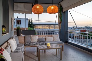 Un balcón con sofá, mesa, lámparas colgantes y vistas a edificios.