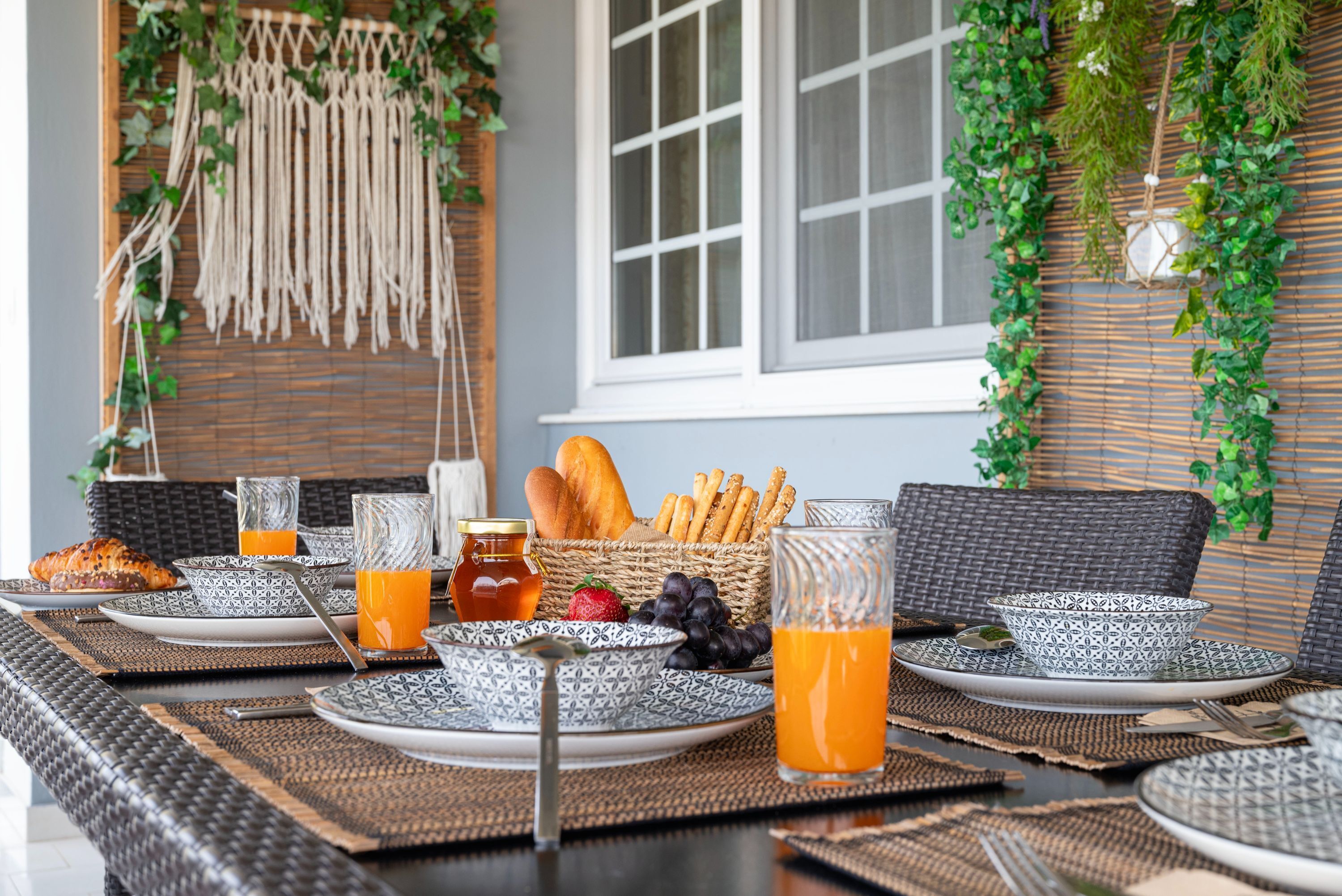 A breakfast setup with wicker furniture, patterned plates, and fresh fruits.