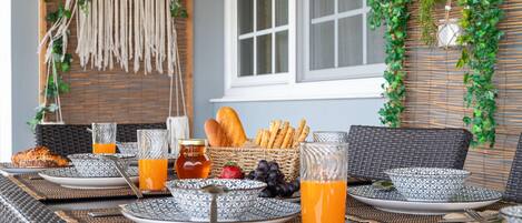 A breakfast setup with wicker furniture, patterned plates, and fresh fruits.