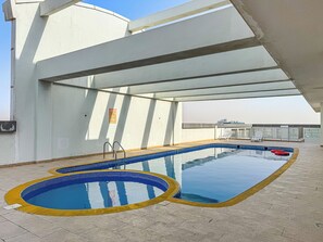 A rooftop pool with clear blue water, a yellow safety border, and a glass ceiling. - Stylish 1BR w/ Balcony, Pool, Gym & Free Parking (Dubai)