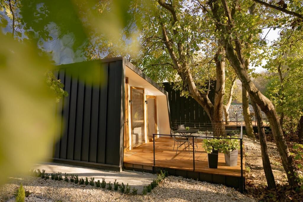 Eine moderne Außenanlage mit Holzterrasse, umgeben von Bäumen und Kies.