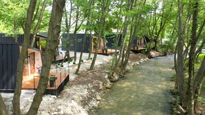 A riverside hotel with modern architecture, outdoor seating, and a natural setting. - Blisku do Gradot Riverfront Cabins (Varvara)