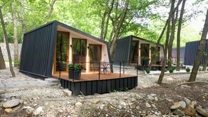 Two modern cabins with large windows, outdoor seating, and a gravel ground. - Blisku do Gradot Riverfront Cabins (Varvara)
