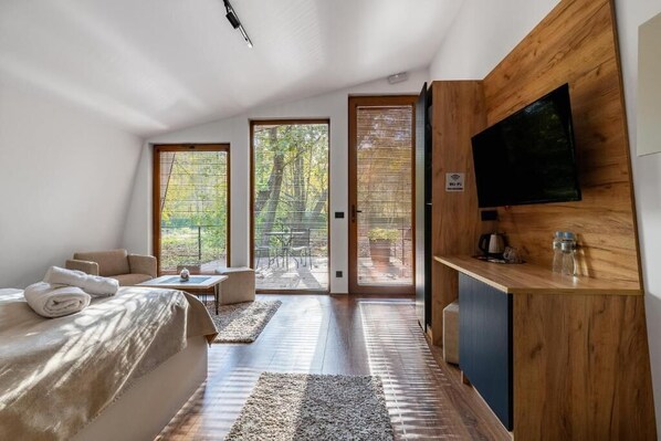 Un dormitorio moderno con una cama grande, un escritorio de madera y un televisor montado en la pared.