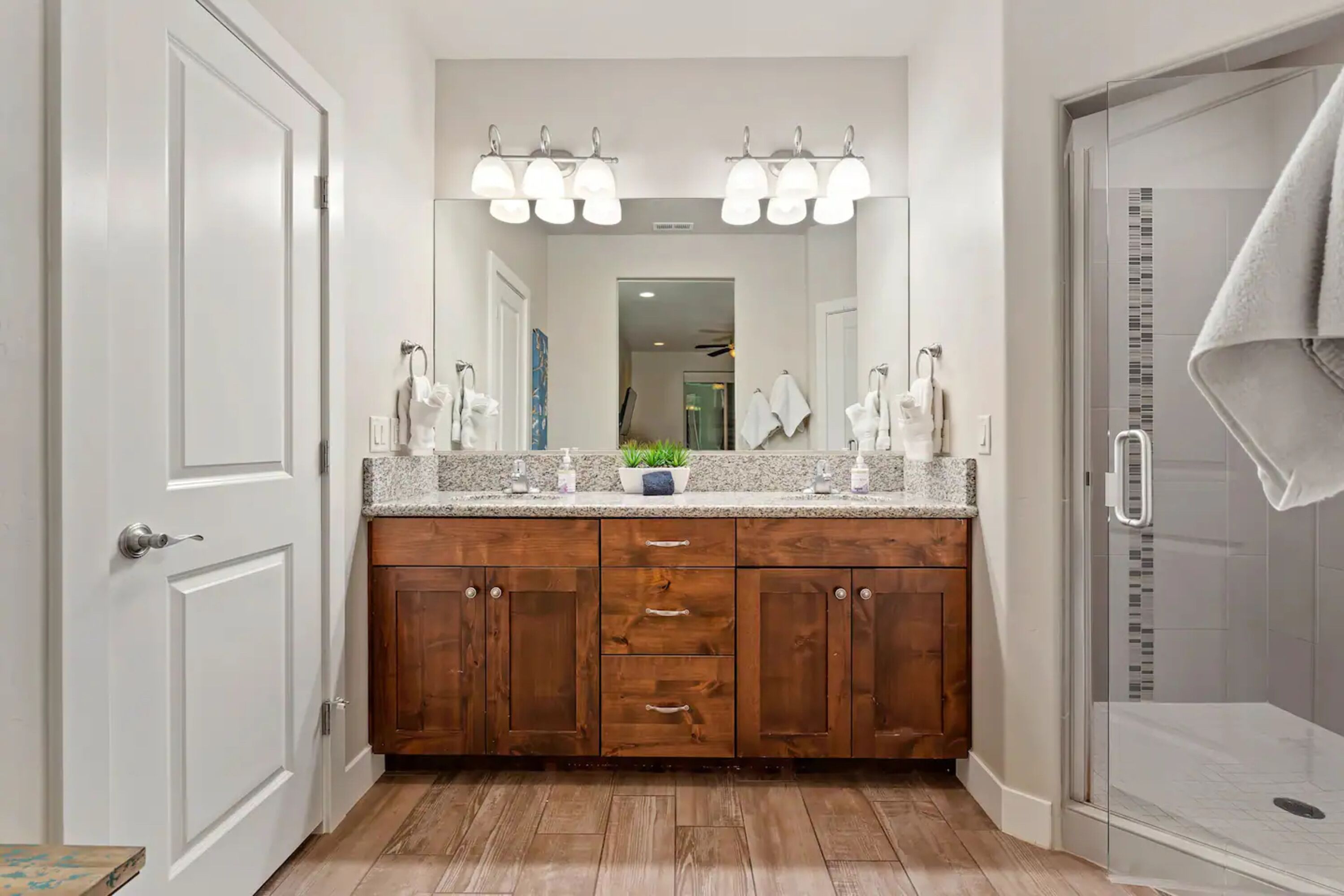 Une salle de bain avec des meubles en bois, un grand miroir et un espace douche.