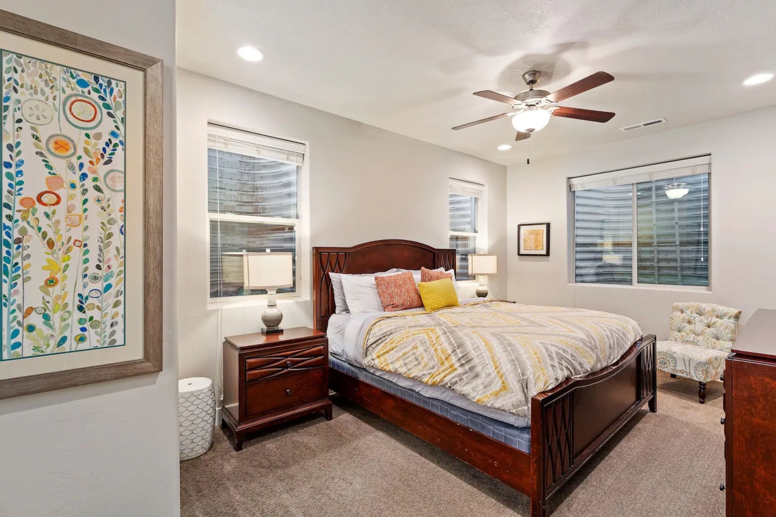 A bedroom with a wooden bed, a ceiling fan, and a large window with blinds.