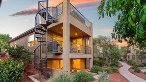 A multi-story building with a spiral staircase, outdoor seating, and a landscaped garden. - Entire Home Paradise Pools 2 King Suites (Ivins)