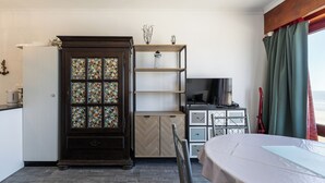 Una habitación de hotel compacta con un armario de madera, un televisor y un comedor.