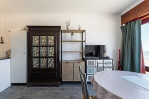 Ein kleines Hotelzimmer mit einem Holzkabinett, einem Fernseher und einem Essbereich.