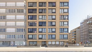Un edificio de varios pisos con balcones, ventanas amplias y una entrada a nivel de calle.