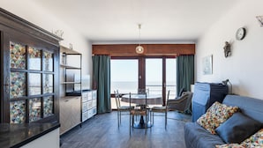 Una sala de estar moderna con comedor, ventanas amplias y vista al mar.