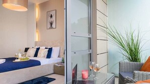A modern bedroom with a bed, bedside table, laptop, and a glass partition.
